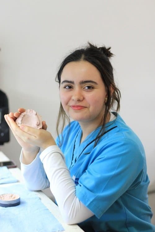 Estudiante del Instituto Técnico Dental de Puebla mostrando su modelo de prótesis dental durante clase práctica.