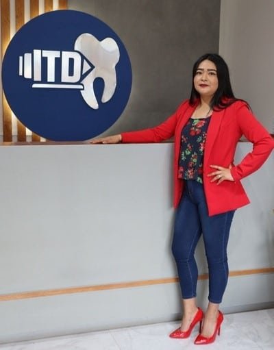 maestra sobre mesa de recepción de itd con el logo de la insitucion en la pared