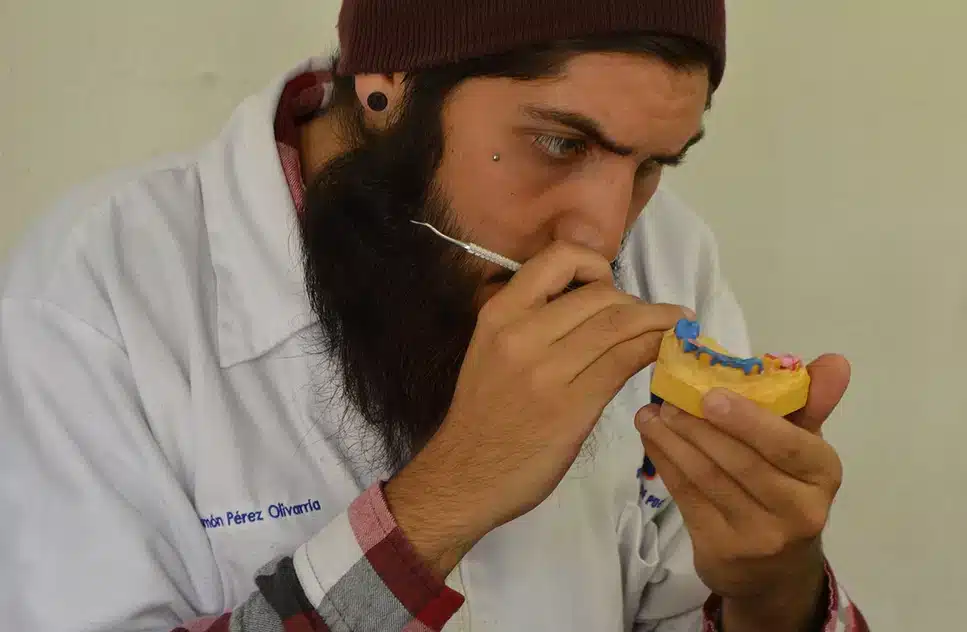 Estudiante en curso de prótesis dental trabajando en un modelo dental durante práctica en laboratorio.