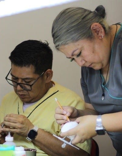 dos profesores realizando un trabajo de confección durante clase